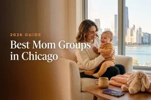 A mom holding her baby at a welcoming Chicago mom group meetup with the city skyline and lakefront behind them, for a guide to the best mom groups in Chicago for 2026