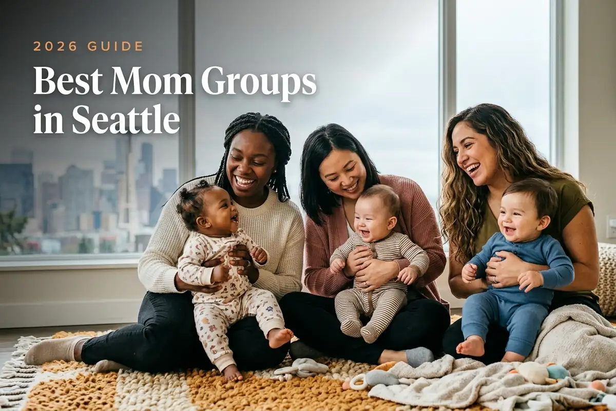 Three diverse moms holding their babies at a welcoming mom group meetup in Seattle, with the Seattle skyline with the Space Needle under soft gray-blue light behind them, illustrating a guide to the best mom groups in Seattle for 2026