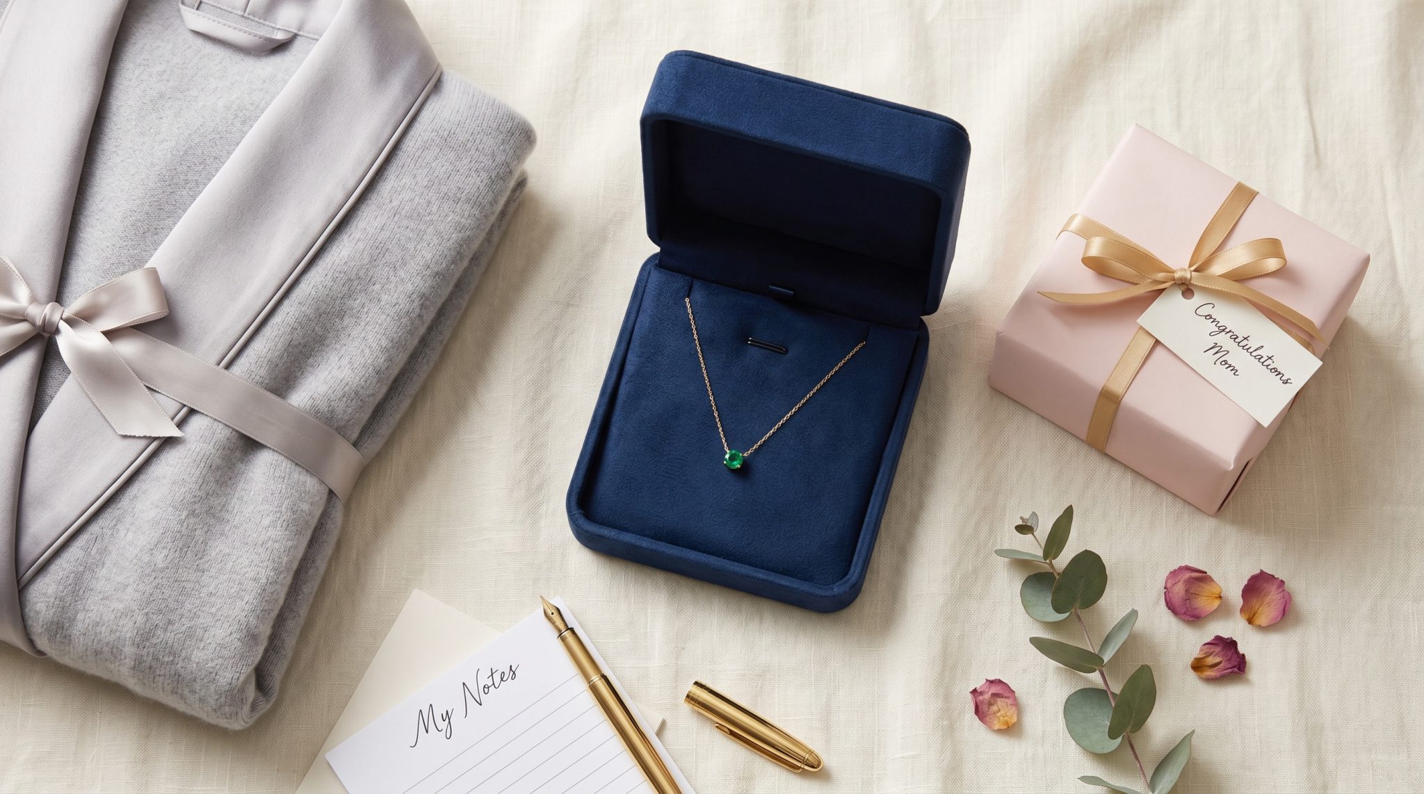 Birthstone necklace in a jewelry box with wrapped push present gifts for a new mom