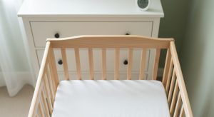 A baby sleeping on their back in a bare safe crib in a comfortably cool room