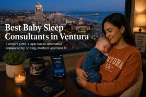 A mother cradling her sleeping baby by a window over the Ventura skyline at dusk, best baby sleep consultants in Ventura