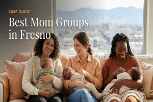 Cover image for a 2026 guide: 'Best Mom Groups in Fresno' showing three smiling moms holding babies on a couch with a city view behind them.