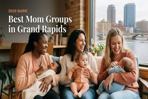 Three smiling mothers on a couch with their babies, by a window overlooking Grand Rapids, for the 2026 guide to best mom groups in Grand Rapids