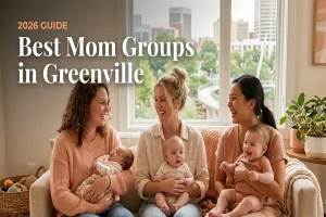 Three smiling moms with babies on a cozy sofa in a bright living room, promoting Greenville's 2026 guide to the best mom groups.