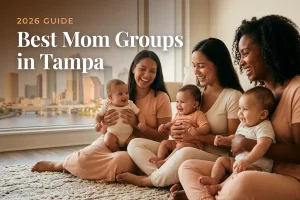 Three diverse moms holding their babies at a welcoming mom group meetup in Tampa, with the Tampa skyline along the waterfront in warm daylight behind them, illustrating a guide to the best mom groups in Tampa for 2026