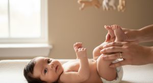 A parent gently bicycling a calm newborn's legs on a changing mat