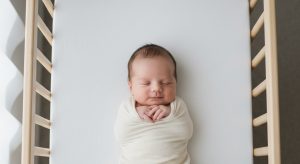 Swaddled newborn sleeping on their back in a bare safe crib