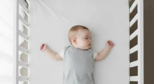 Baby sleeping safely on their back in a completely bare crib with a fitted sheet only