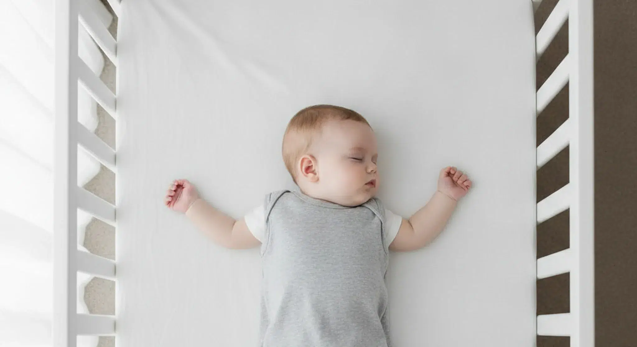 Baby sleeping safely on their back in a completely bare crib with a fitted sheet only
