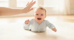 Smiling awake baby lying on their back in a bare crib during the day