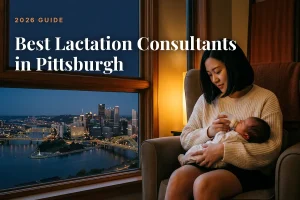 Best lactation consultants in Pittsburgh 2026 guide cover, mother feeding her baby beside a window with the Pittsburgh skyline at night