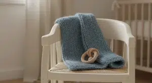 Small blue knitted blanket and wooden toy on a nursery chair in soft daylight