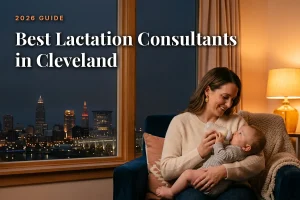 Best lactation consultants in Cleveland guide cover: mother bottle feeding her baby in a warm evening living room with the Cleveland skyline through the window