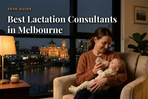 Best lactation consultants in Melbourne guide cover: mother bottle feeding her baby in a warm evening living room with the Melbourne skyline through the window
