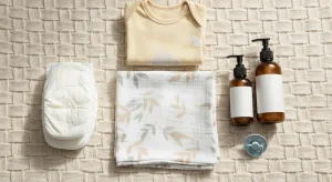 An assortment of free baby samples including swaddle, lotion, pacifier, onesie, and diapers on a blanket