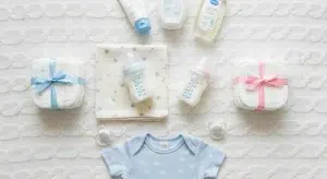 An assortment of free baby items including bottles, a swaddle, and a onesie arranged on a blanket