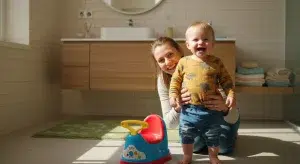 A happy toddler standing next to a small potty chair in a bright bathroom