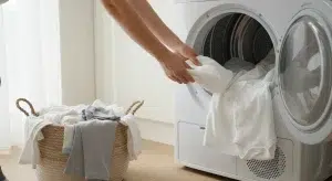 Baby Bed Bugs What They Look Like Bites on Babies and How to Get Rid of Them Safely | Betteroo A parent loading plain white baby sheets and clothes into a clothes dryer in a bright laundry room