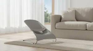 Contemporary living room with a gray lounge chair on a beige rug in front of a large window with sheer white curtains.