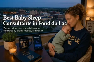 Mother holding sleeping baby by a window over downtown at dusk, baby sleep consultants in Fond du Lac