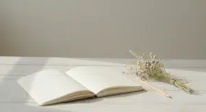 Unique Girl Names 160 Rare and Beautiful Picks with Meanings | Betteroo Blank notebook, pencil and a small posy of dried wildflowers on a pale wooden table