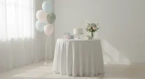when to Have a Baby Shower Best Weeks Invitations and Timing Tips | Betteroo Pastel birthday party table with a small cake on a pedestal, wrapped gifts, balloons, and a bouquet of flowers in soft light.